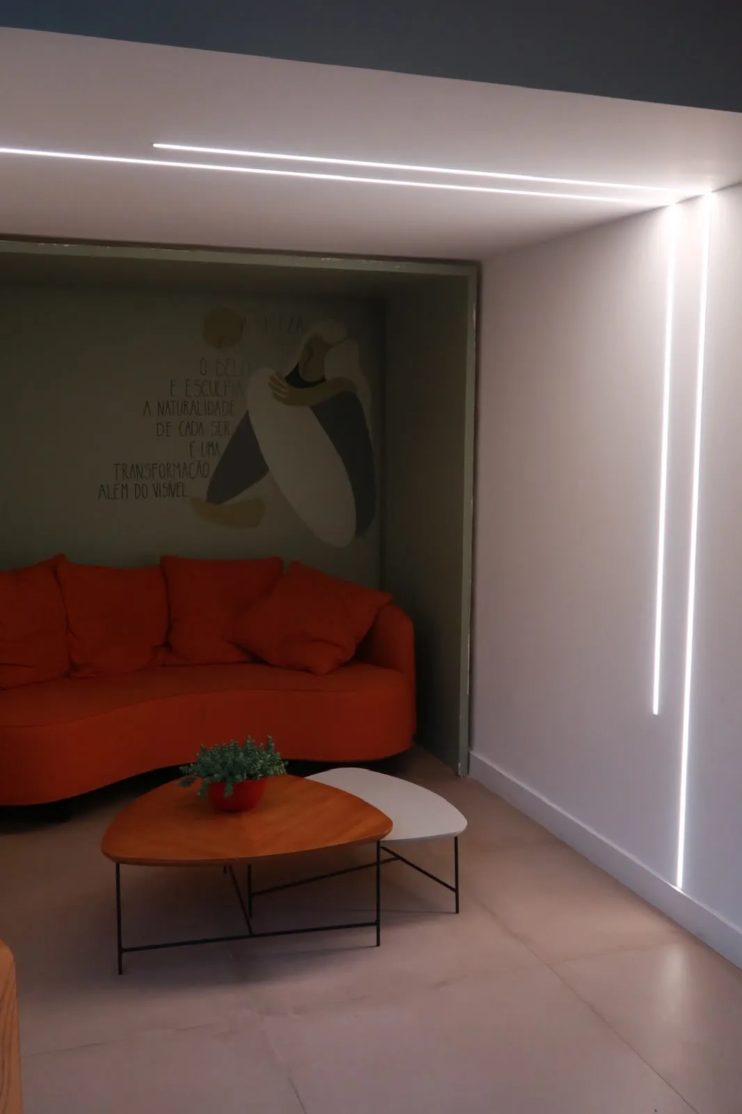 Sala de espera com sofá laranja e mesa de madeira